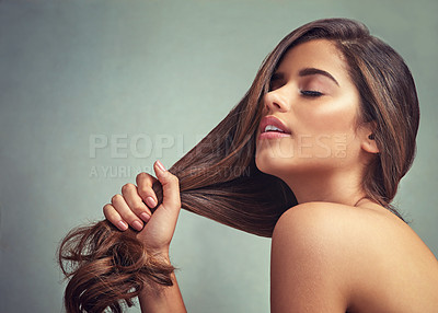 Buy stock photo Studio shot of a beautiful woman with long locks posing against a grey background