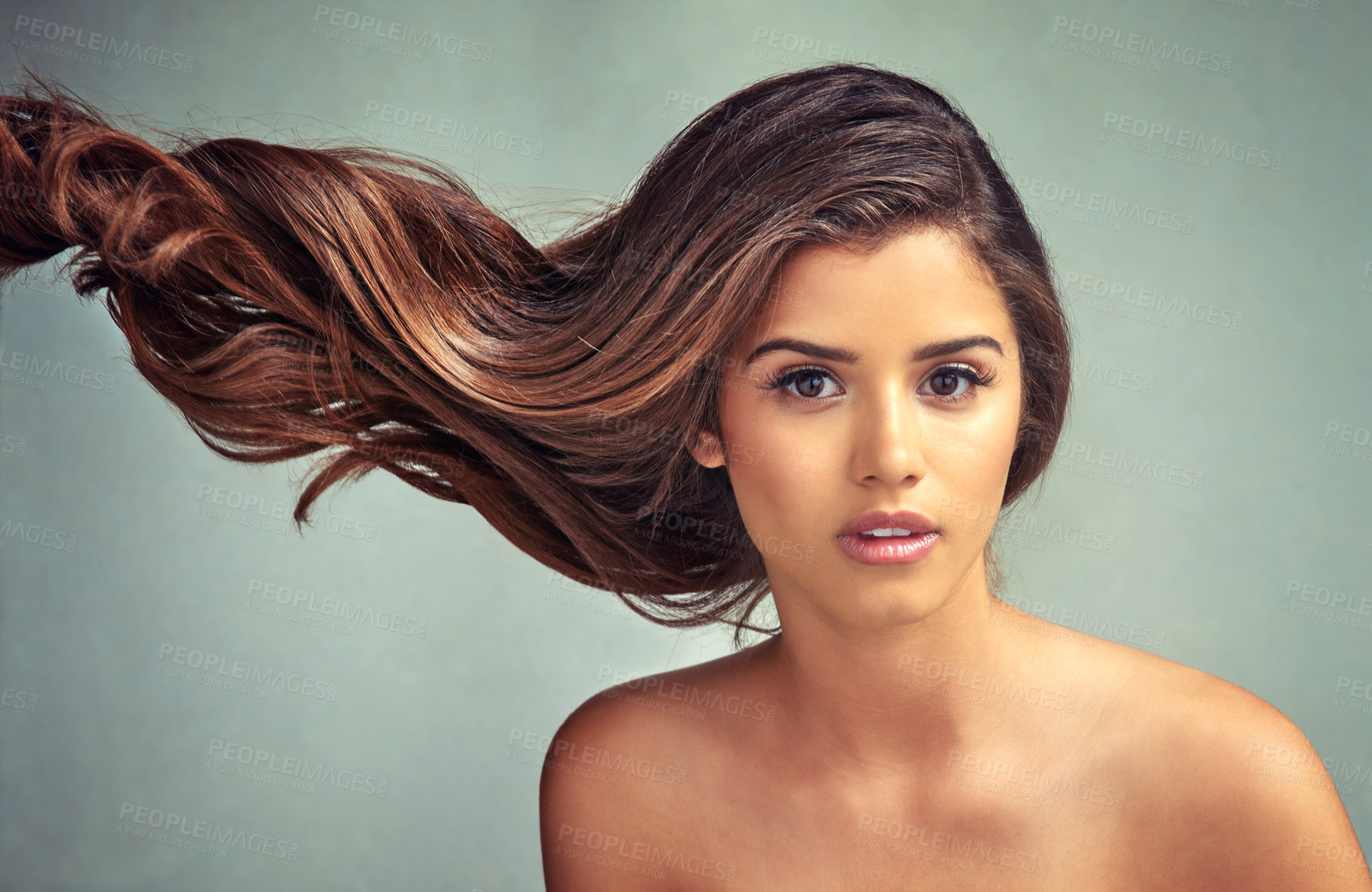 Buy stock photo Studio portrait of a beautiful woman with long locks posing against a grey background