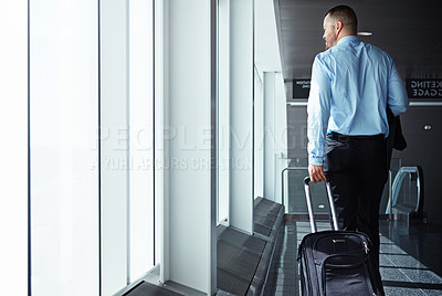 Buy stock photo Shot of a businessman walking down an airport corridor while on a business trip