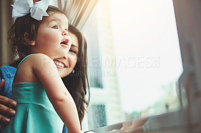 Buy stock photo Cropped shot of a mother and her adorable little daughter looking out the window at home