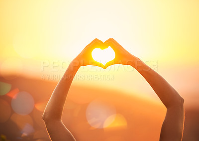 Buy stock photo Shot of an unidentifiable woman's hands making a heart shape over a sunset landscape