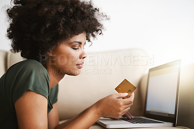 Buy stock photo Cropped shot of a woman using her laptop on the sofa at home while holding a bankcard