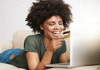 Buy stock photo Cropped shot of a woman using her laptop on the sofa at home while holding a bankcard