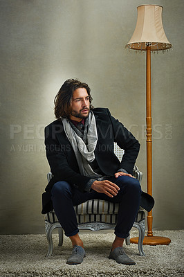 Buy stock photo Shot of a stylishly dressed man sitting on a chair in the studio