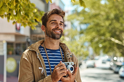 Buy stock photo Shot of a happy tourist taking pictures while exploring a foreign city on his own