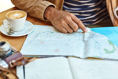 Buy stock photo Shot of an unidentifiable tourist looking at maps and travel journals while enjoying coffee at a cafe