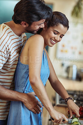 Buy stock photo Shot of an affectionate young couple cooking together in their kitchen at home