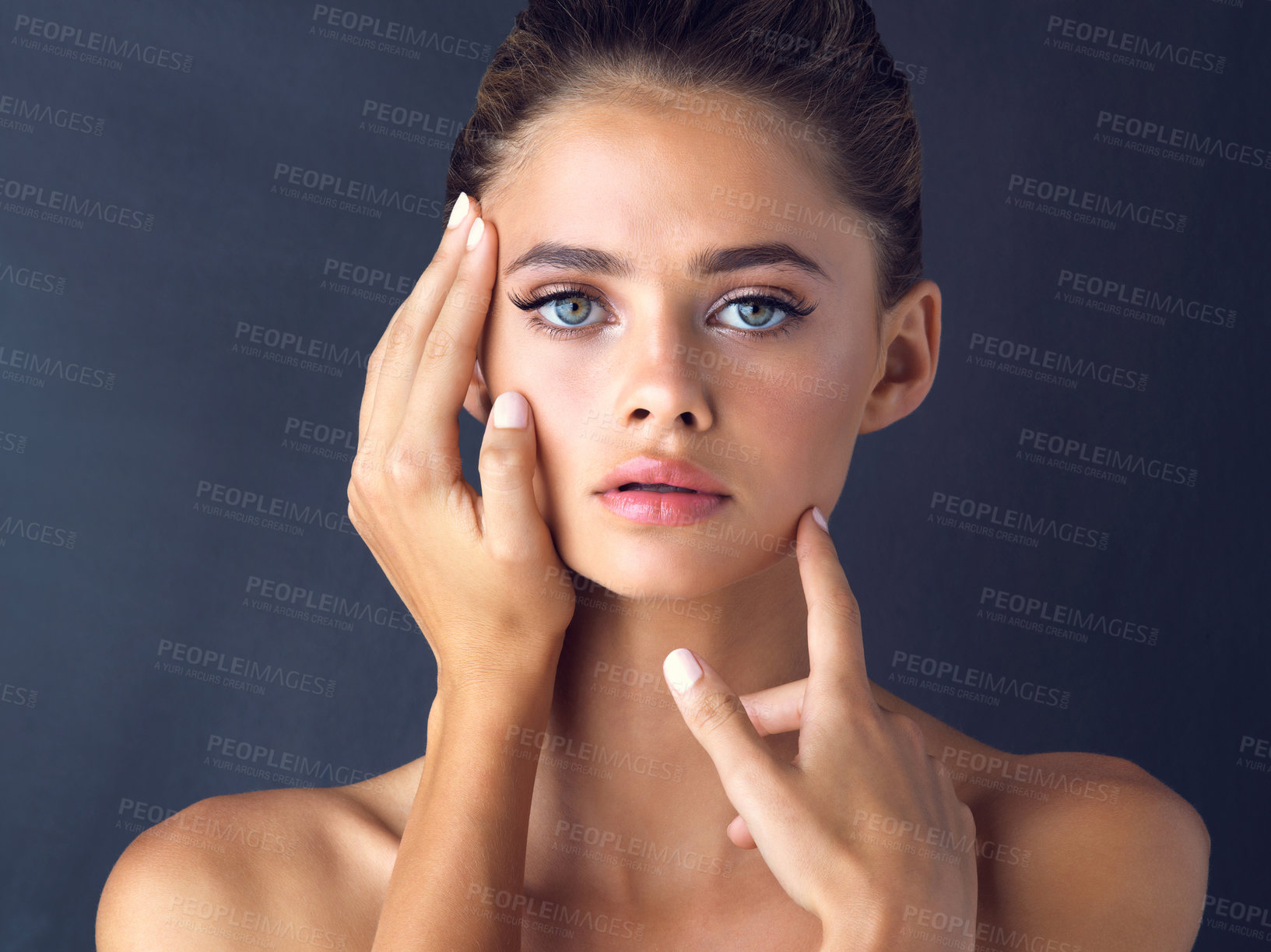 Buy stock photo Studio shot of an attractive young woman posing and touching her face on two different places