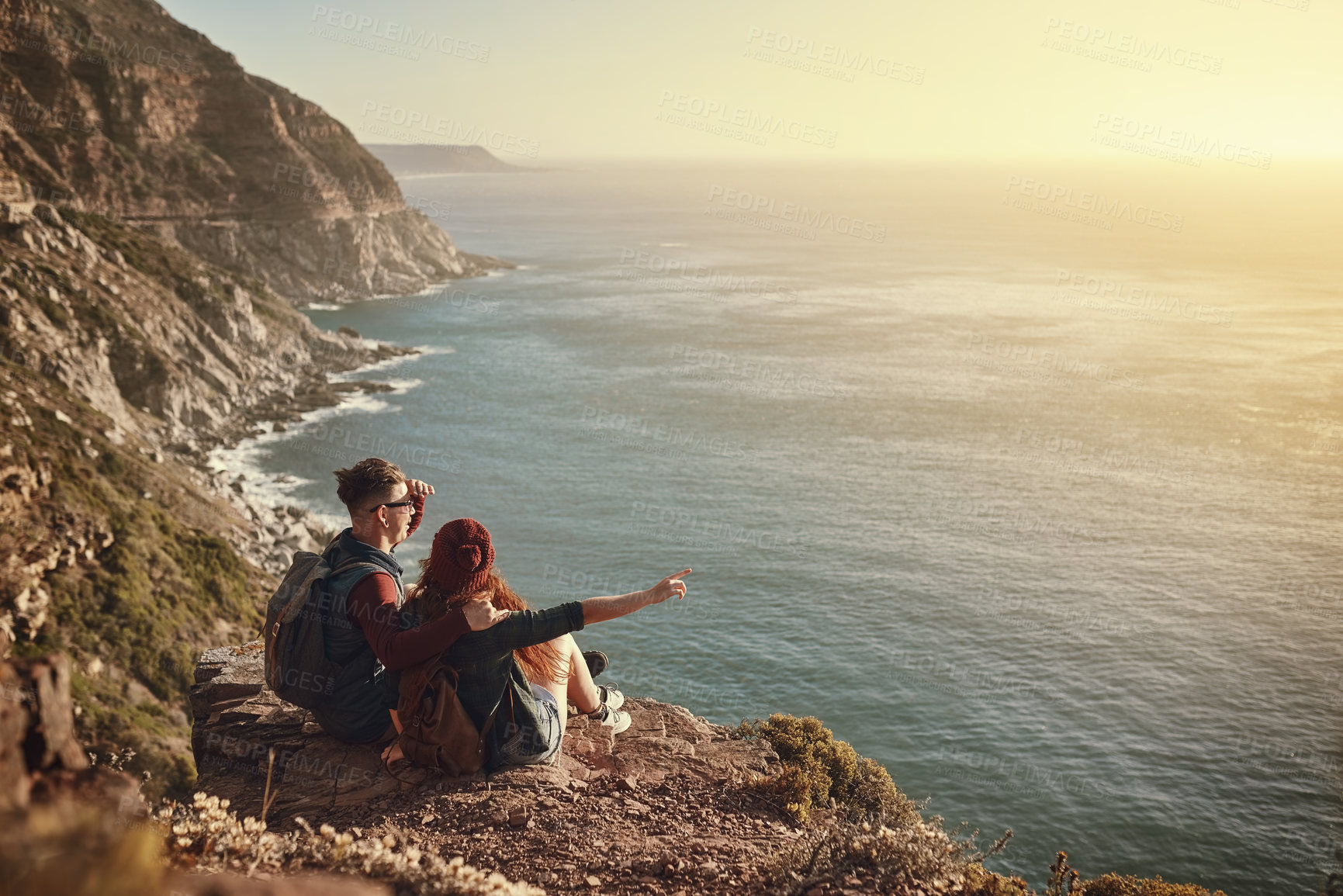 Buy stock photo High angle shot of an affectionate young couple taking in the view from a mountaintop