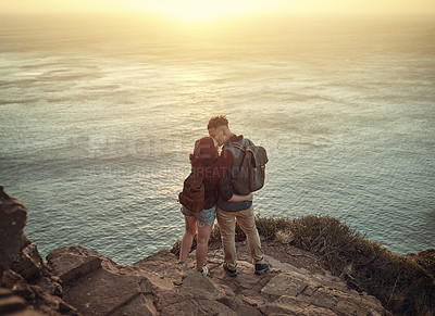 Buy stock photo High angle shot of an affectionate young couple kissing on a mountaintop