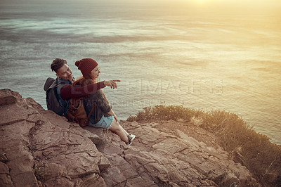 Buy stock photo Couple, hiking and talking on outdoor mountain, love and fitness adventure by view of ocean. People, pointing and speaking on cliff in nature, trekking and conversation or backpacking on holiday