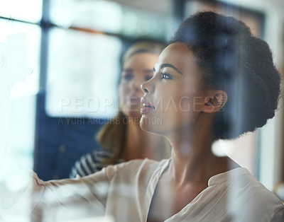 Buy stock photo Shot of two colleagues having a brainstorming session in a modern office