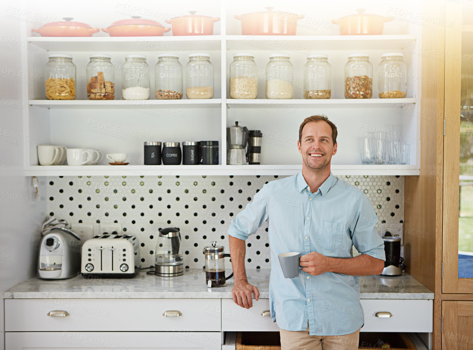 Buy stock photo Shot of a laid-back bachelor enjoying a cup of coffee in his kitchen at home