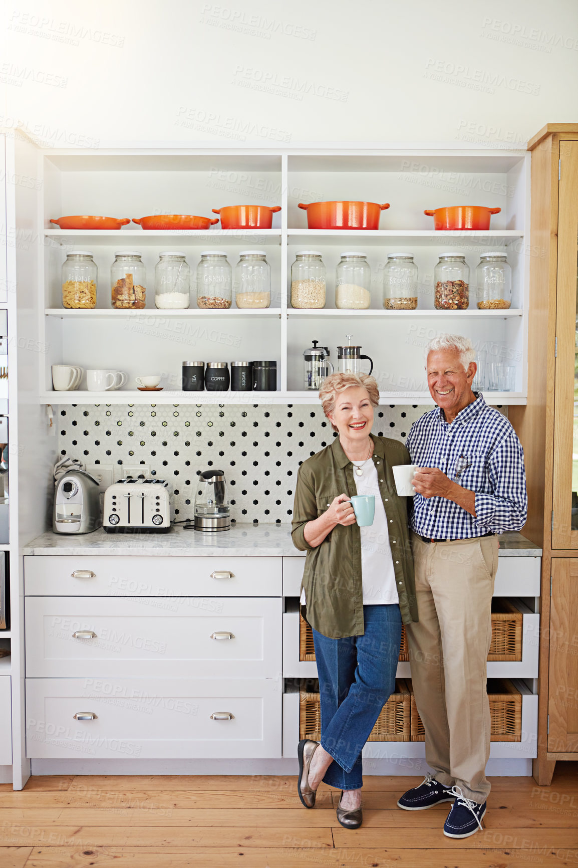 Buy stock photo Shot of a happy senior couple bonding over coffee in their kitchen at home