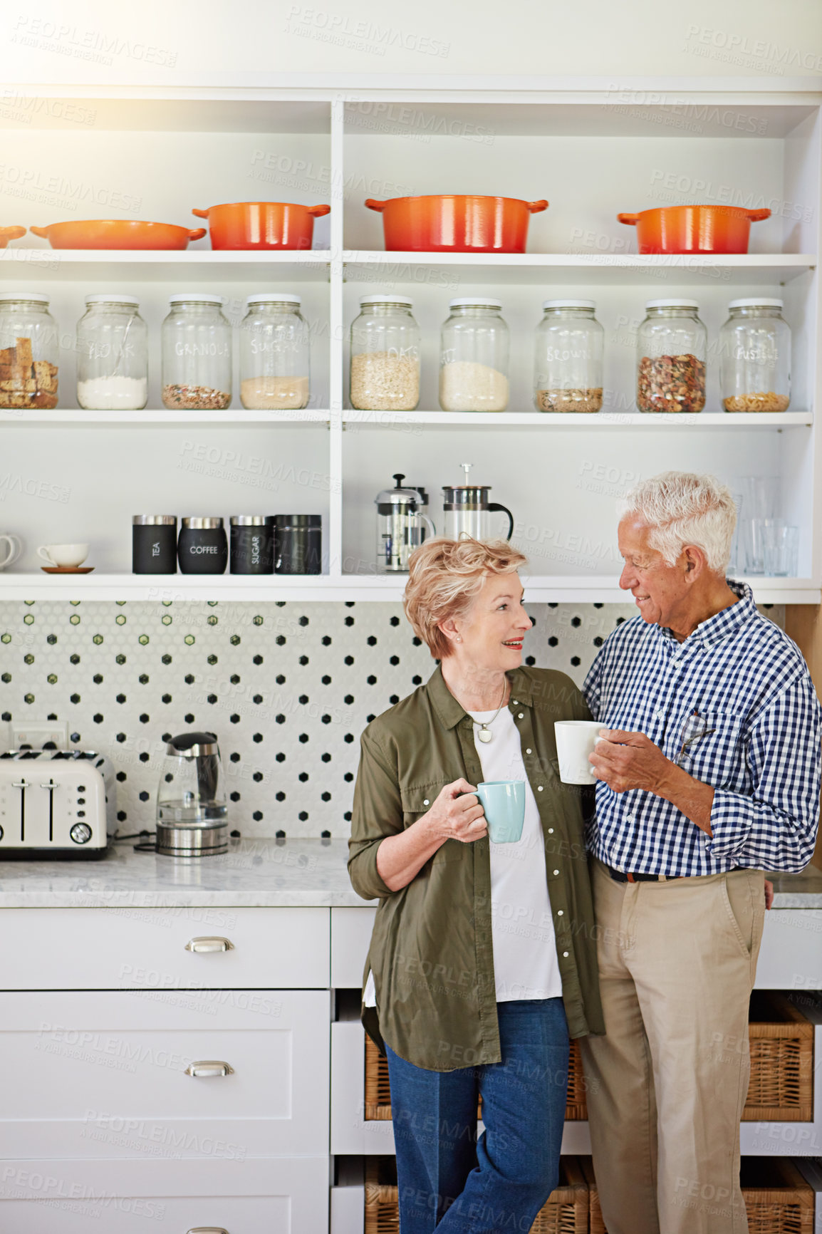 Buy stock photo Shot of a happy senior couple bonding over coffee in their kitchen at home