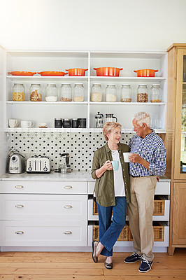 Buy stock photo Shot of a happy senior couple bonding over coffee in their kitchen at home