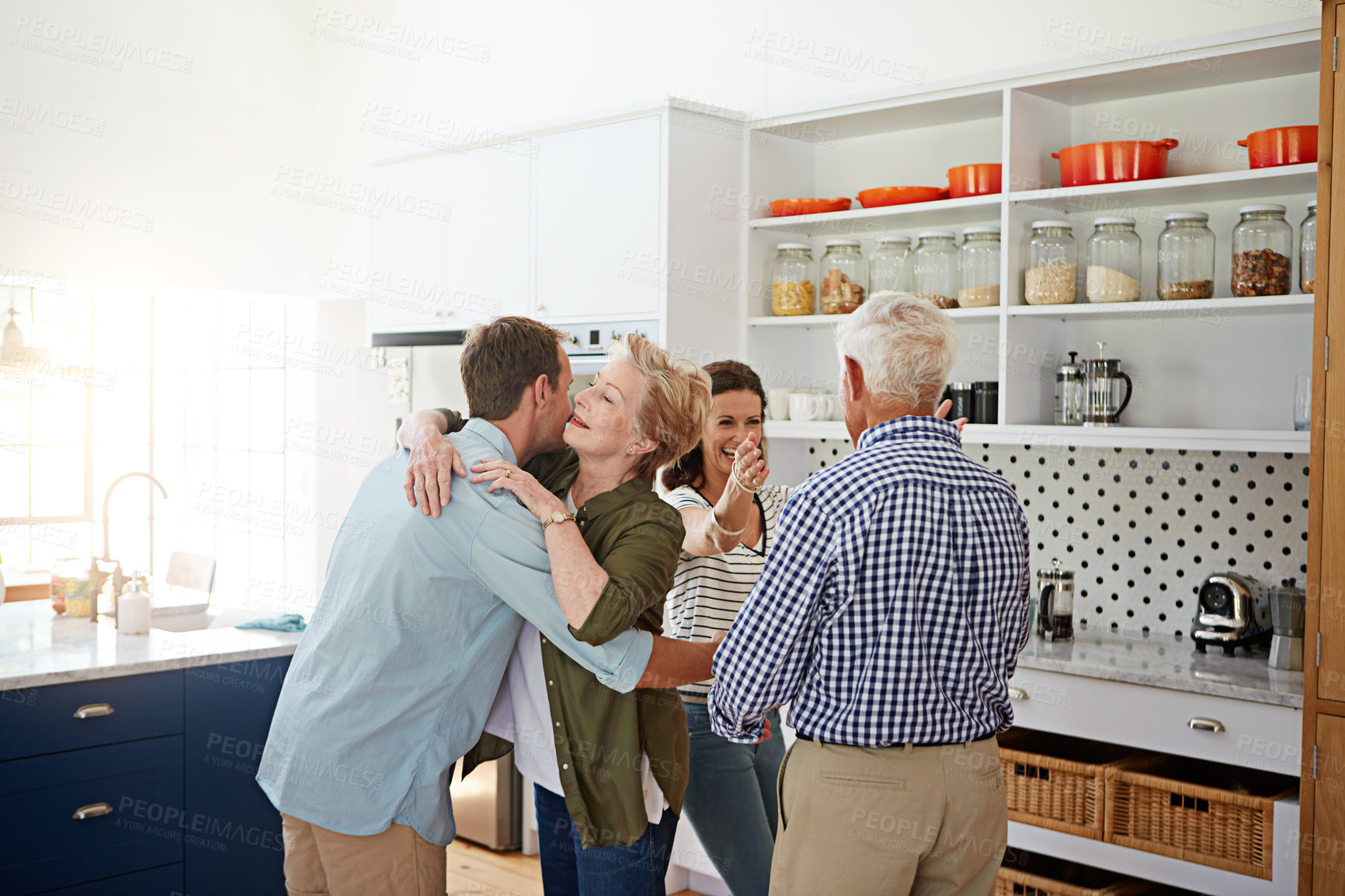 Buy stock photo Shot of a loving family greeting each other with hugs in the kitchen at home