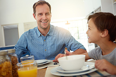 Buy stock photo Portrait of a happy father having breakfast with his young son in the kitchen at home