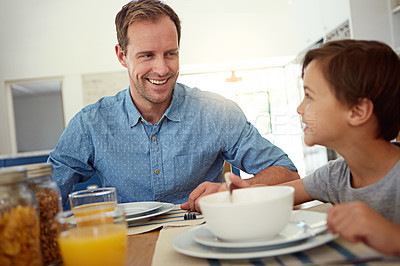 Buy stock photo Shot of a happy father having breakfast with his young son in the kitchen at home