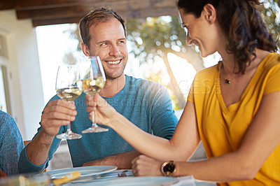 Buy stock photo Shot of a happy couple toasting with wine during a family lunch outdoors