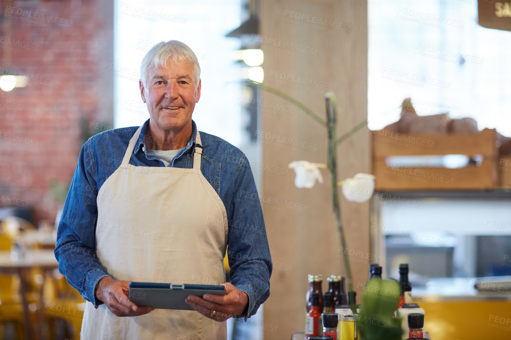 Buy stock photo Portrait of a confident senior business owner posing with an apron on in his coffee shop