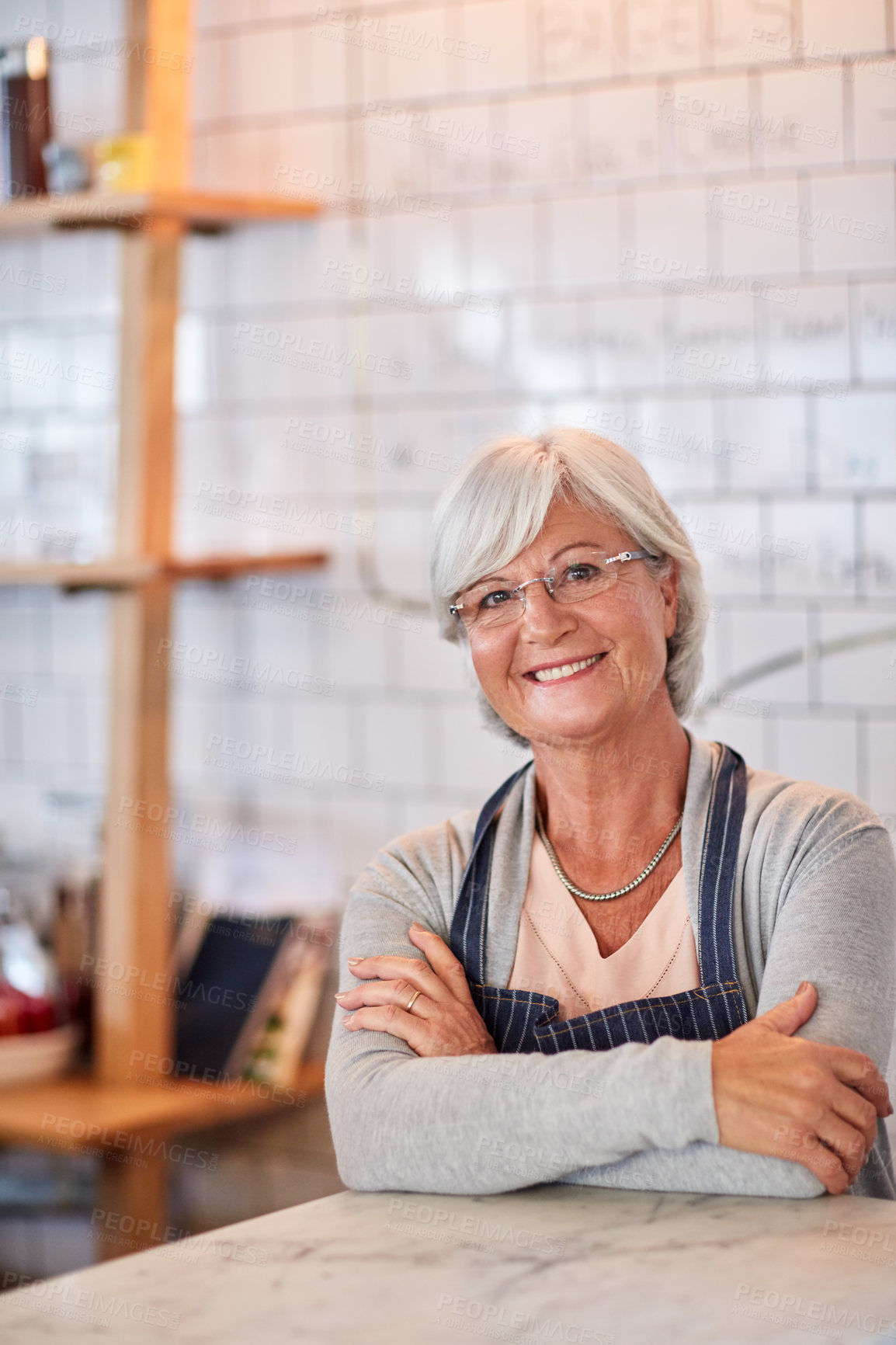 Buy stock photo Portrait of a happy senior business owner posing at the counter in her coffee shop