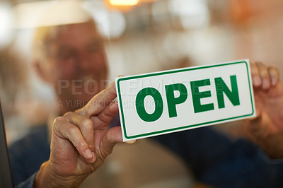 Buy stock photo Shot of a happy senior business owner holding up an open sign in the door of his coffee shop