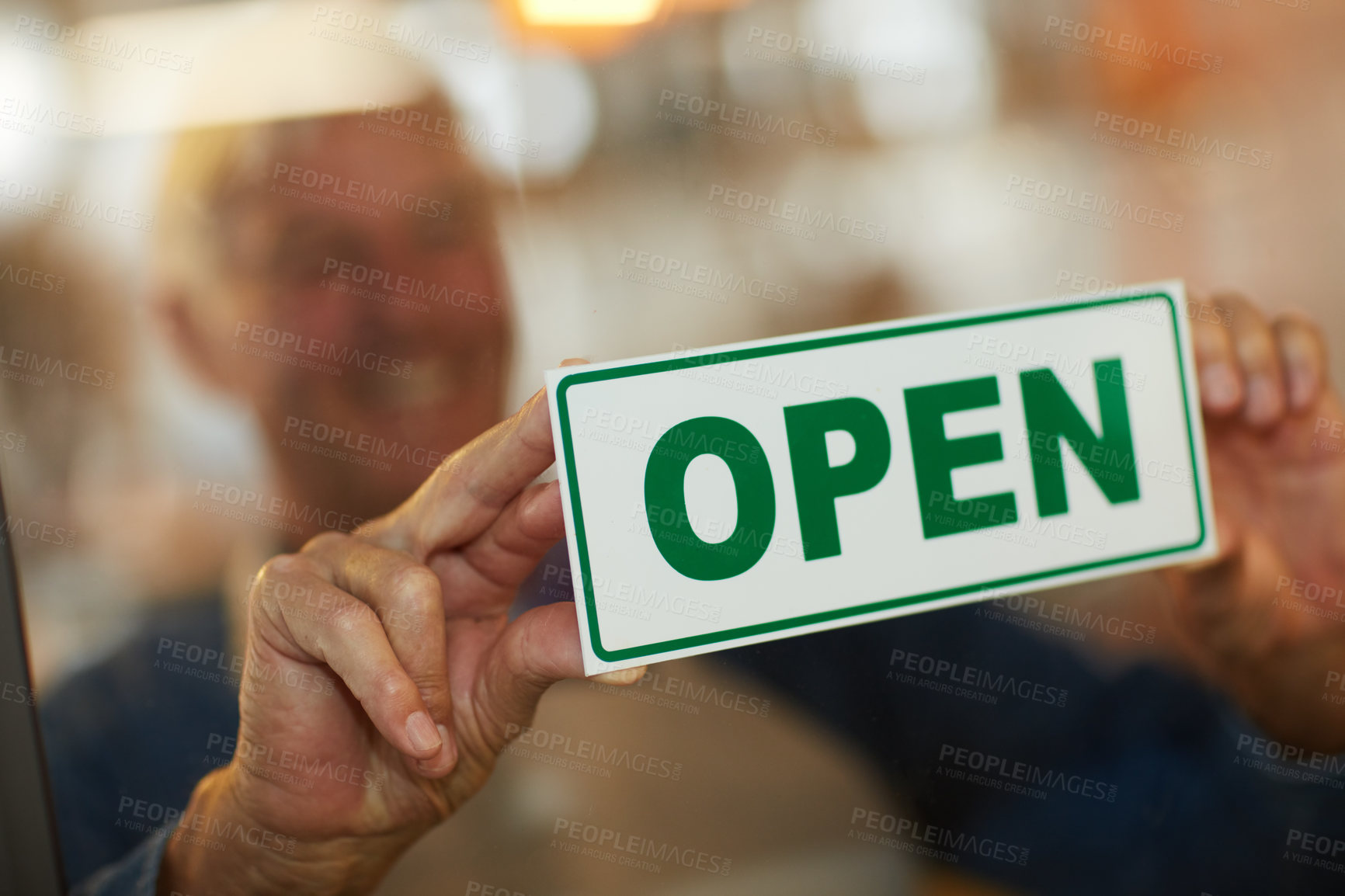 Buy stock photo Shot of a happy senior business owner holding up an open sign in the door of his coffee shop