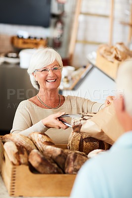 Buy stock photo Shot of a happy senior woman serving a customer in a bakery
