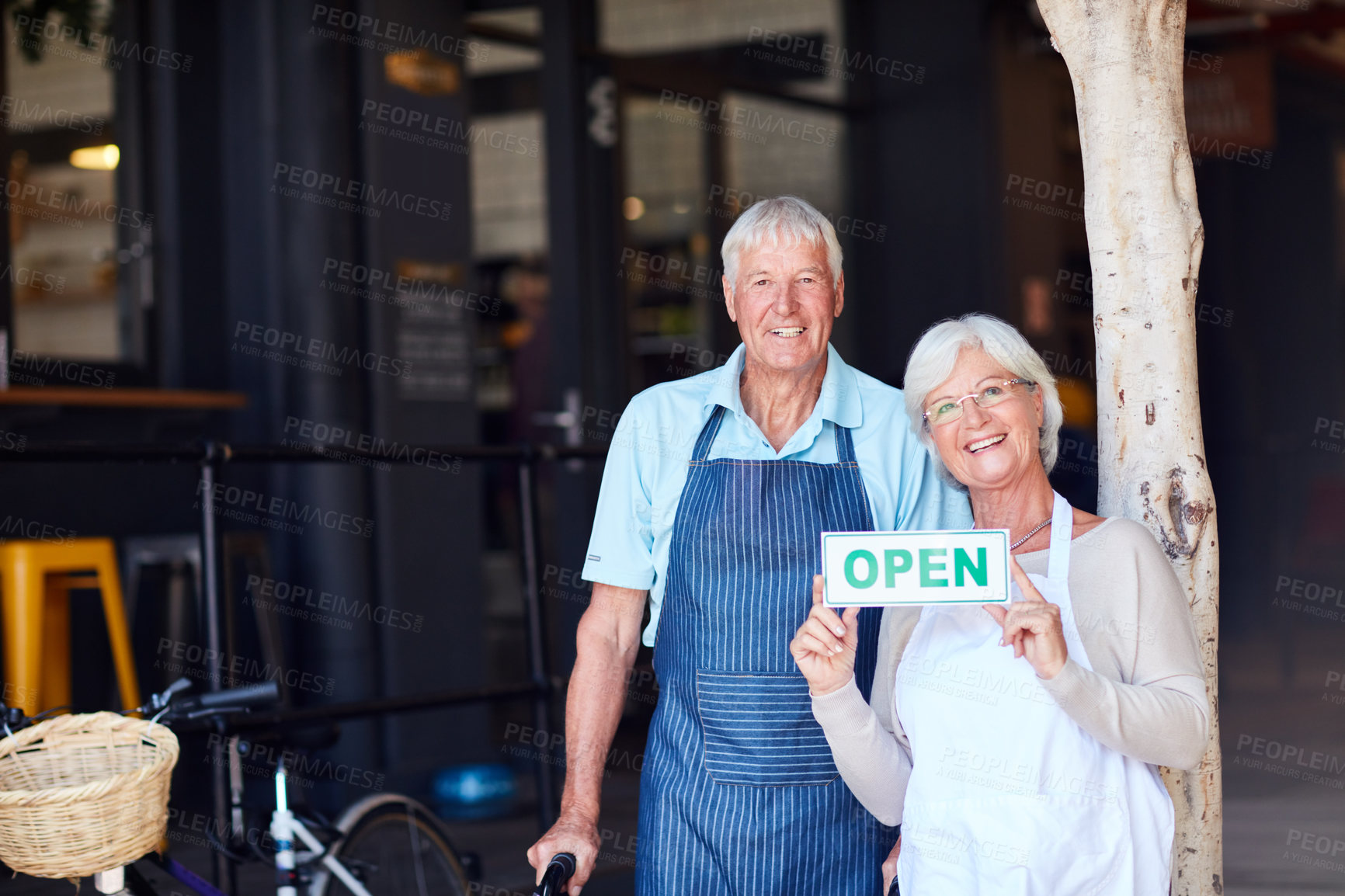 Buy stock photo Portrait of a happy senior couple holding up an open sign in their store