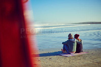 Buy stock photo Rearview shot of a young couple sitting on the beach