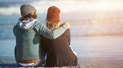 Buy stock photo Rearview shot of a young couple sitting on the beach