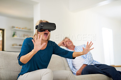 Buy stock photo Cropped shot of a mature woman wearing a VR headset with her husband in the background