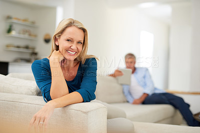 Buy stock photo Portrait of a mature woman relaxing at home with her husband in the background