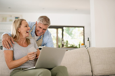 Buy stock photo Shot of a mature couple laughing at something they saw on the laptop