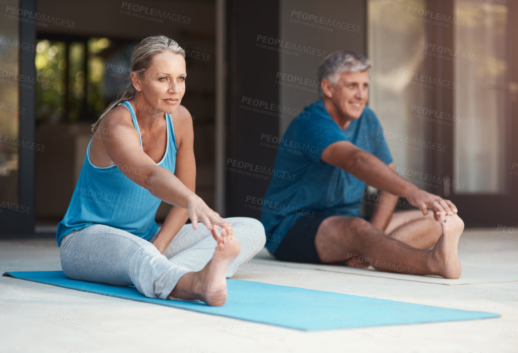 Buy stock photo Shot of a mature and happy couple stretching before they do yoga outside of their home