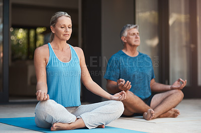 Buy stock photo Shot of a mature couple calmly engaging in a yoga pose with their legs crossed