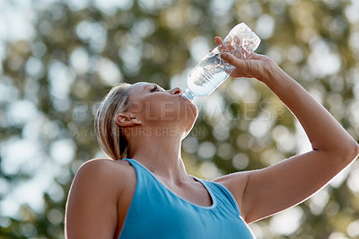 Buy stock photo Shot of mature and fit woman having a drink from a water bottle in the outdoors