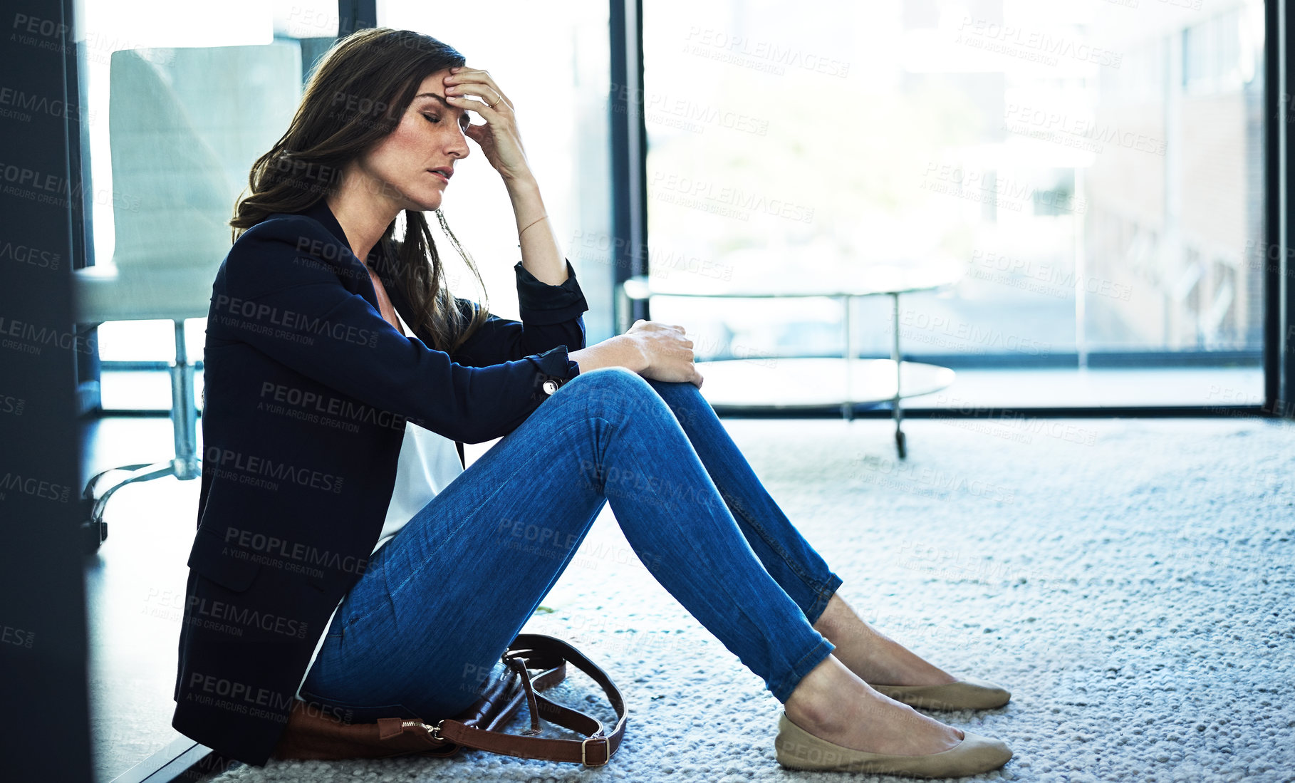 Buy stock photo Shot of a stressed businesswoman sitting on the floor outside the boardroom