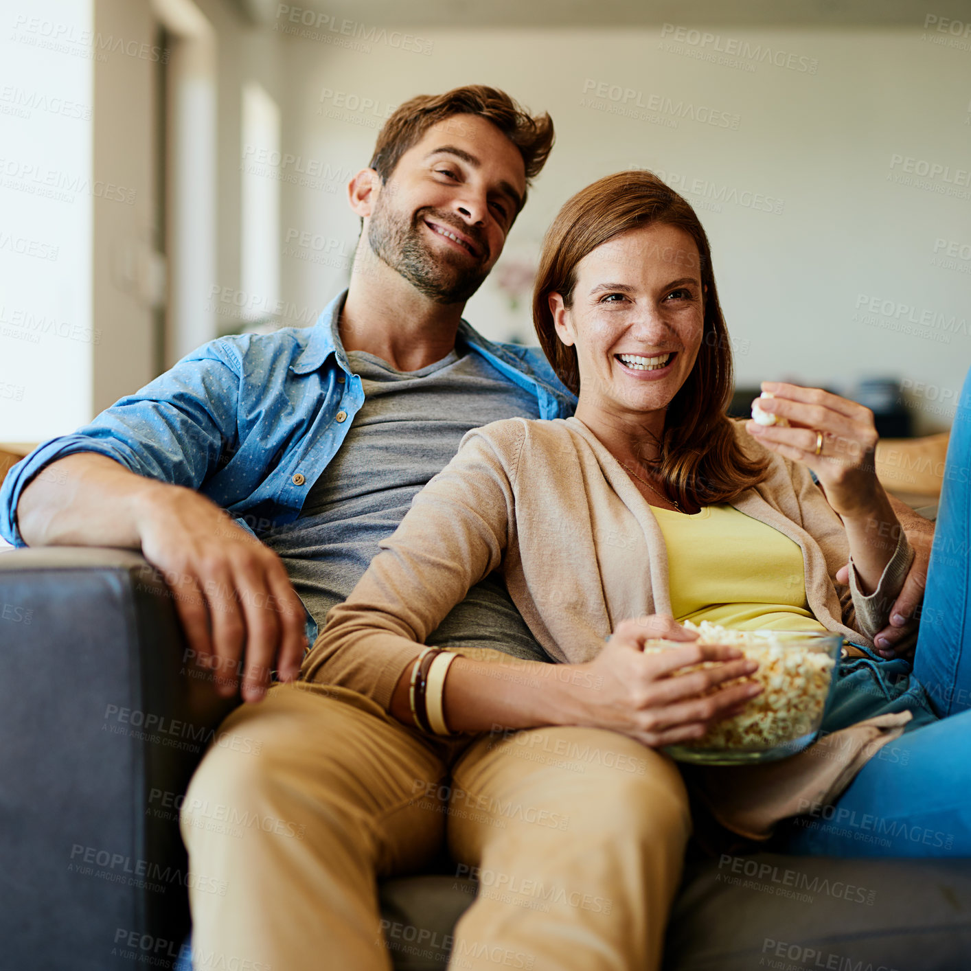 Buy stock photo Couple, smile and relax on sofa with popcorn, funny movie and comedy show at home. Happy woman, man or snack on couch for comfort, popular television series or relationship development in living room