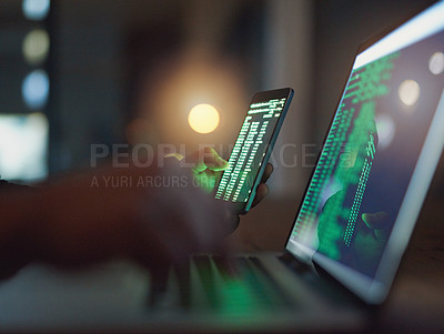 Buy stock photo Shot of an unrecognisable hacker using a cellphone and laptop in the dark