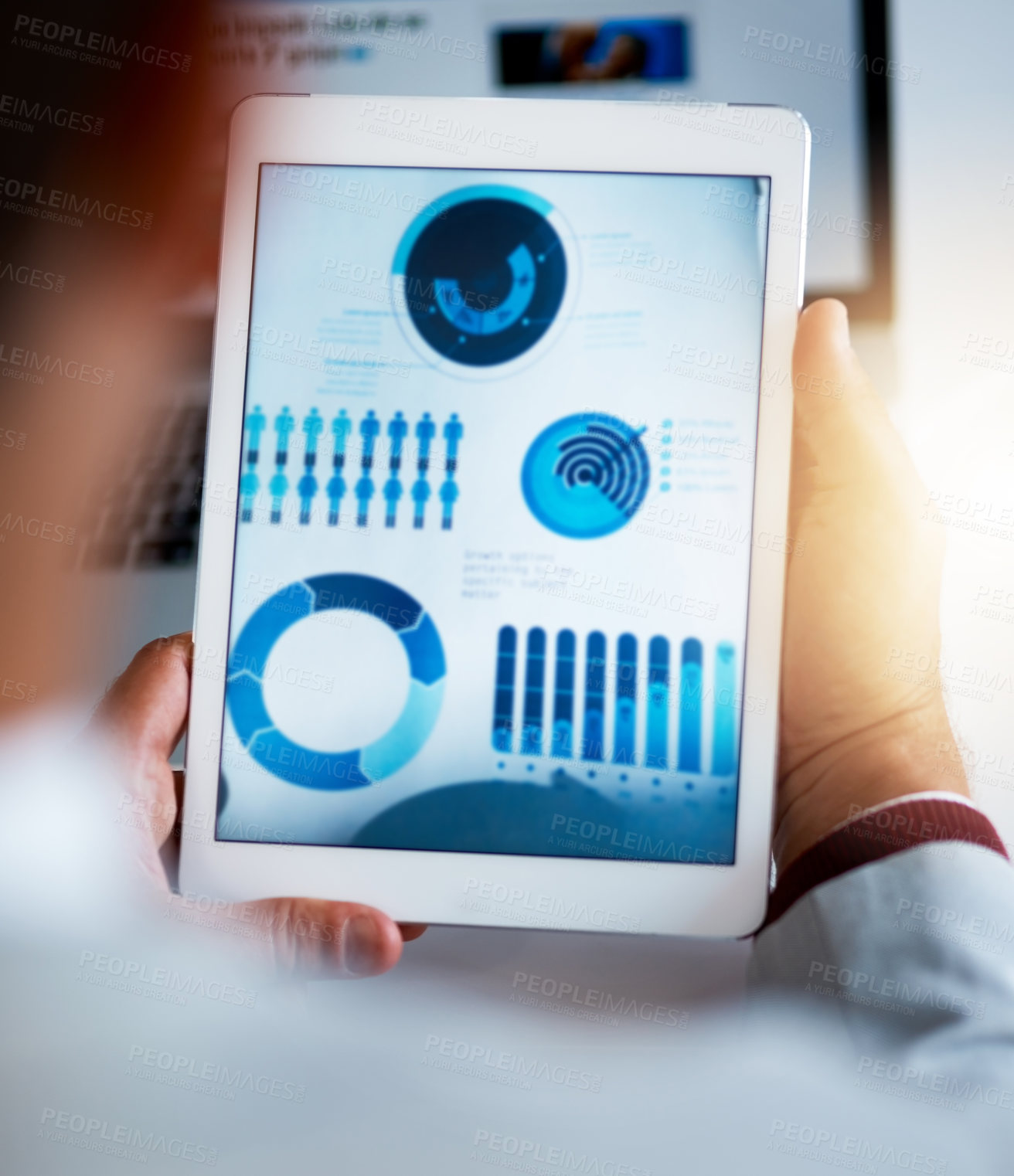 Buy stock photo Rearview shot of an unrecognizable businessmen looking at charts and graphs on his tablet in the office