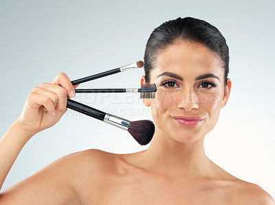 Buy stock photo Studio shot of a beautiful young woman holding makeup brushes against a gray background