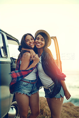 Buy stock photo Shot of two affectionate friends stopping at the beach during their roadtrip