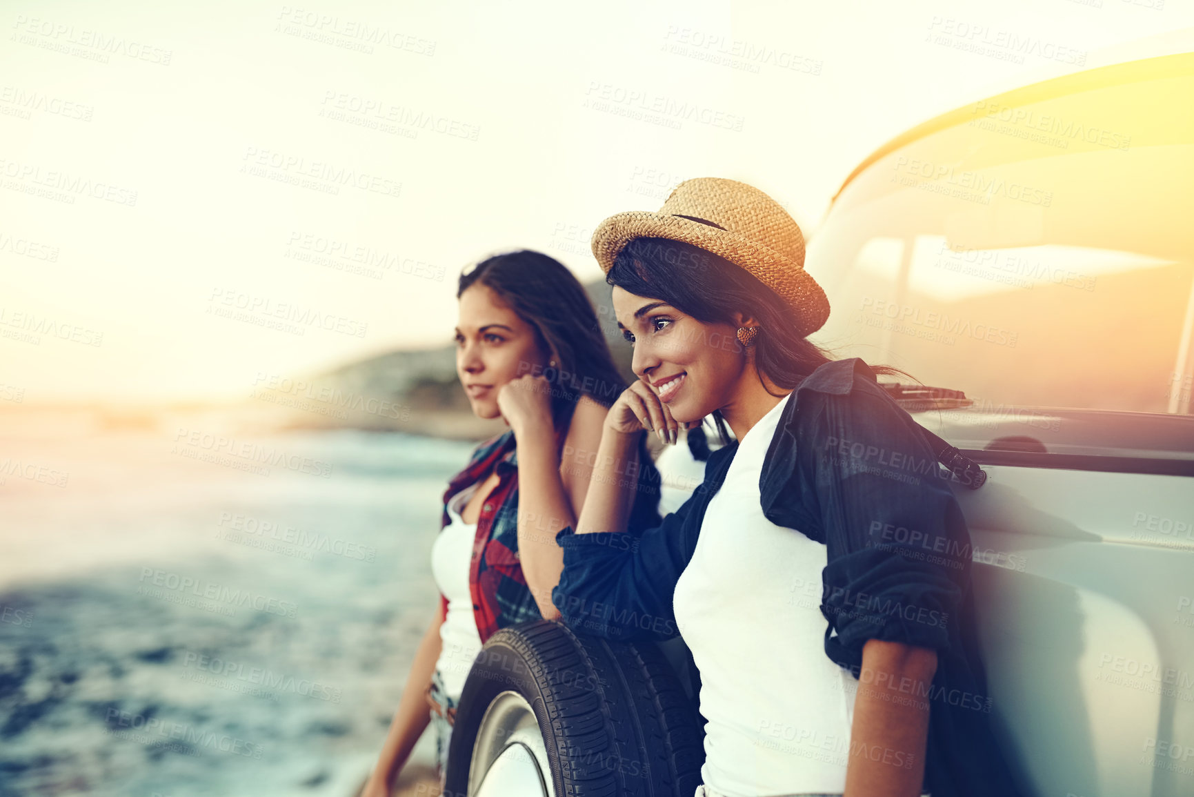 Buy stock photo Shot of two young friends stopping at the beach during their roadtrip