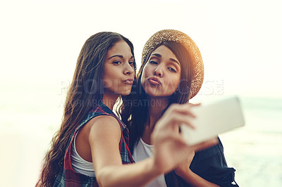 Buy stock photo Shot of two young friends taking a selfie together outdoors