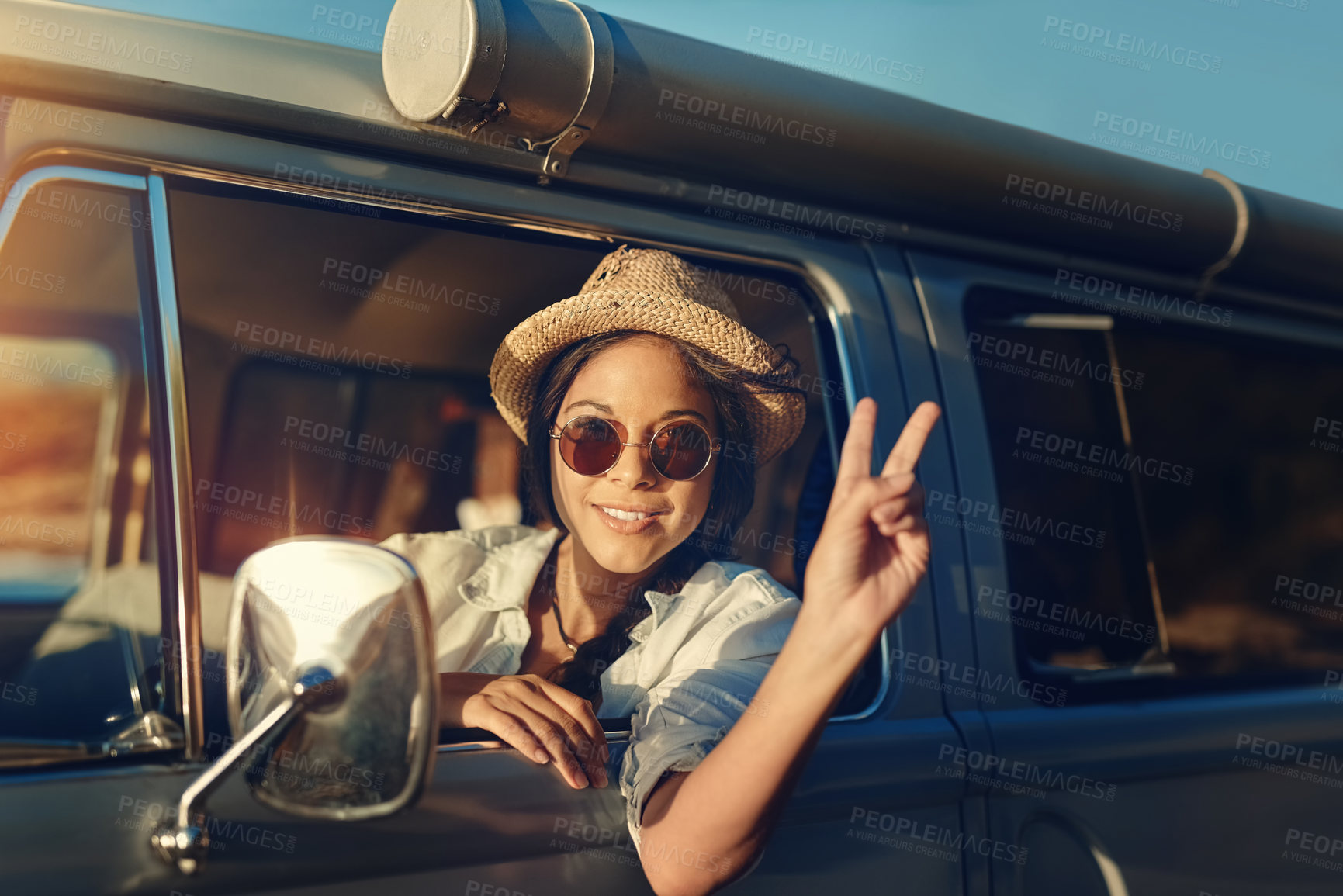 Buy stock photo Shot of a young woman leaning out of a van’s window and showing a peace sign on a roadtrip