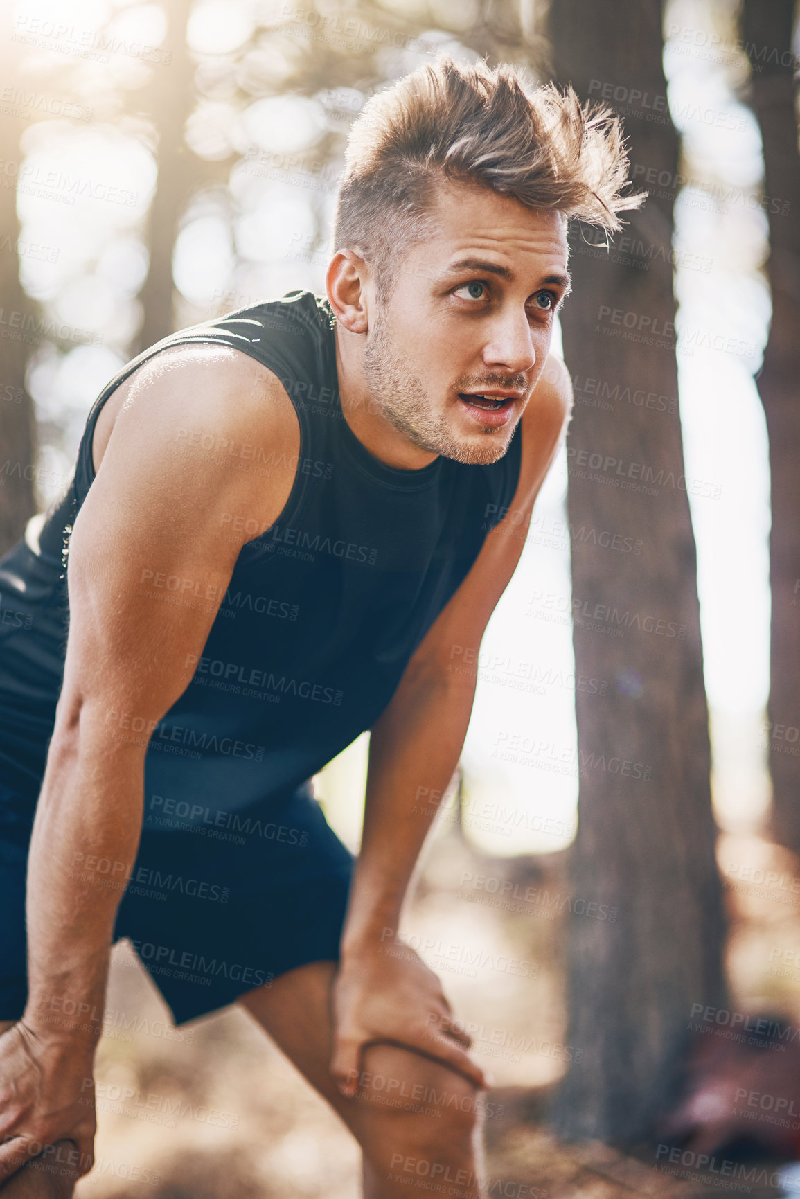 Buy stock photo Shot of a young man resting from a run outside in the forest