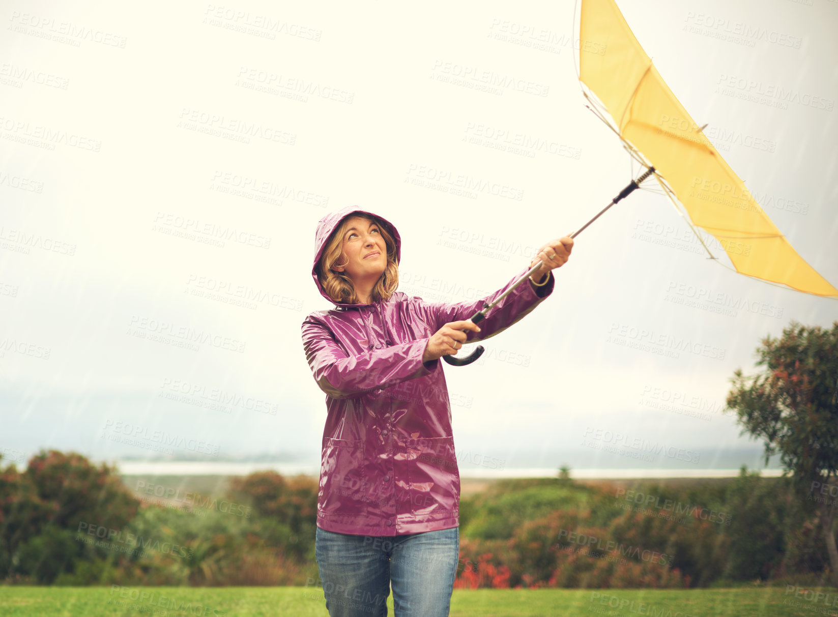 Buy stock photo Shot of a woman standing outside in the rain holding an umbrella looking up in the sky