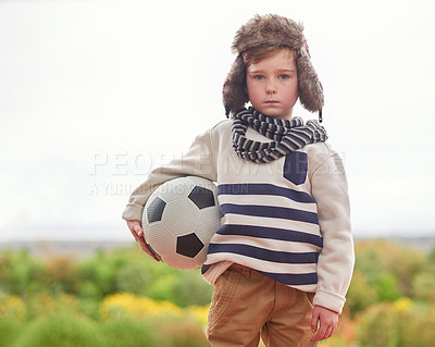 Buy stock photo Shot of a little boy standing outside in rainy weather with his soccer ball